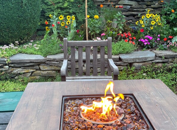 A wooden bench with a fire feature in front of it.