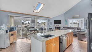A spacious kitchen with a large island, sliding glass doors leading to a dining area, and a built-in TV. - Lagoon-front home just minutes from the beach! (Stafford Township)