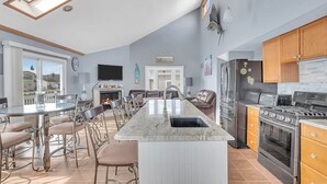 A modern kitchen with a central island, stainless steel appliances, and a dining area with a view. - Lagoon-front home just minutes from the beach! (Stafford Township)