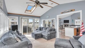 A spacious living area with a grey sectional sofa, a ceiling fan, and a skylight. - Lagoon-front home just minutes from the beach! (Stafford Township)