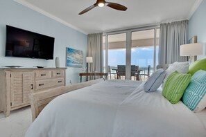Habitación de hotel con una cama grande, televisión de pantalla plana, cómoda de madera y balcón con vistas.