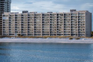 Un hotel de varios pisos con balcones, cerca de una masa de agua.