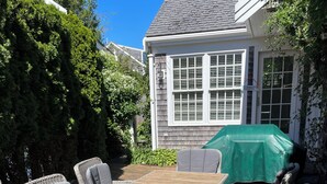 Un patio al aire libre con mobiliario de mimbre, una mesa de madera y un mantel verde.