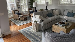 Una sala de estar moderna con un sofá modular, una mesita redonda y una silla de mimbre.