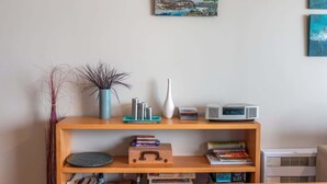 A wooden shelf with books, a vase, and a clock. - The Sands - Apartment 23 - Onetangi Beach (Waiheke Island)