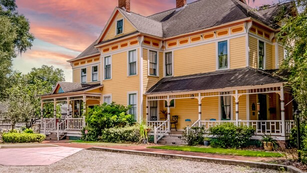 A yellow two-story house with a porch, chimney, and multiple windows. - The Laurel Oak Inn Bed and Breakfast (Gainesville)