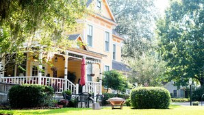 A yellow house with a porch, a dining area with chairs, and a small garden. - The Laurel Oak Inn Bed and Breakfast (Gainesville)