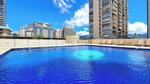Una piscina con vistas a rascacielos y montañas al fondo.