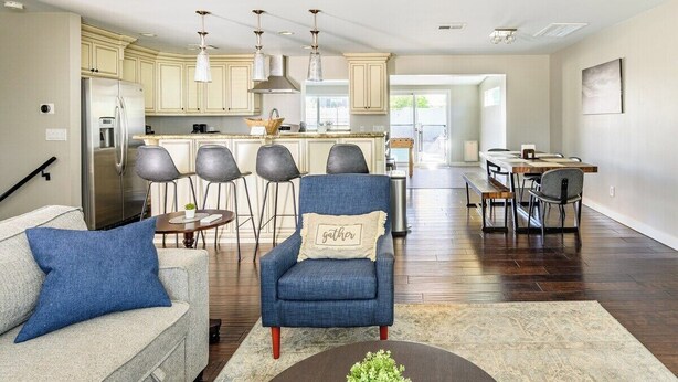 A modern kitchen with a dining area, featuring a sofa, armchairs, and a coffee table.