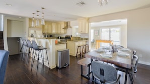 A modern kitchen with bar stools, a dining table set for four, and a compact refrigerator.