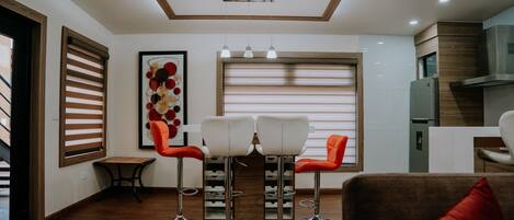 A modern kitchen with a built-in oven, a dining area with two chairs, and a large window with blinds.