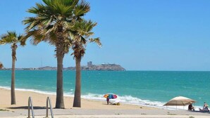 Vista da piscina com praia e palmeiras.