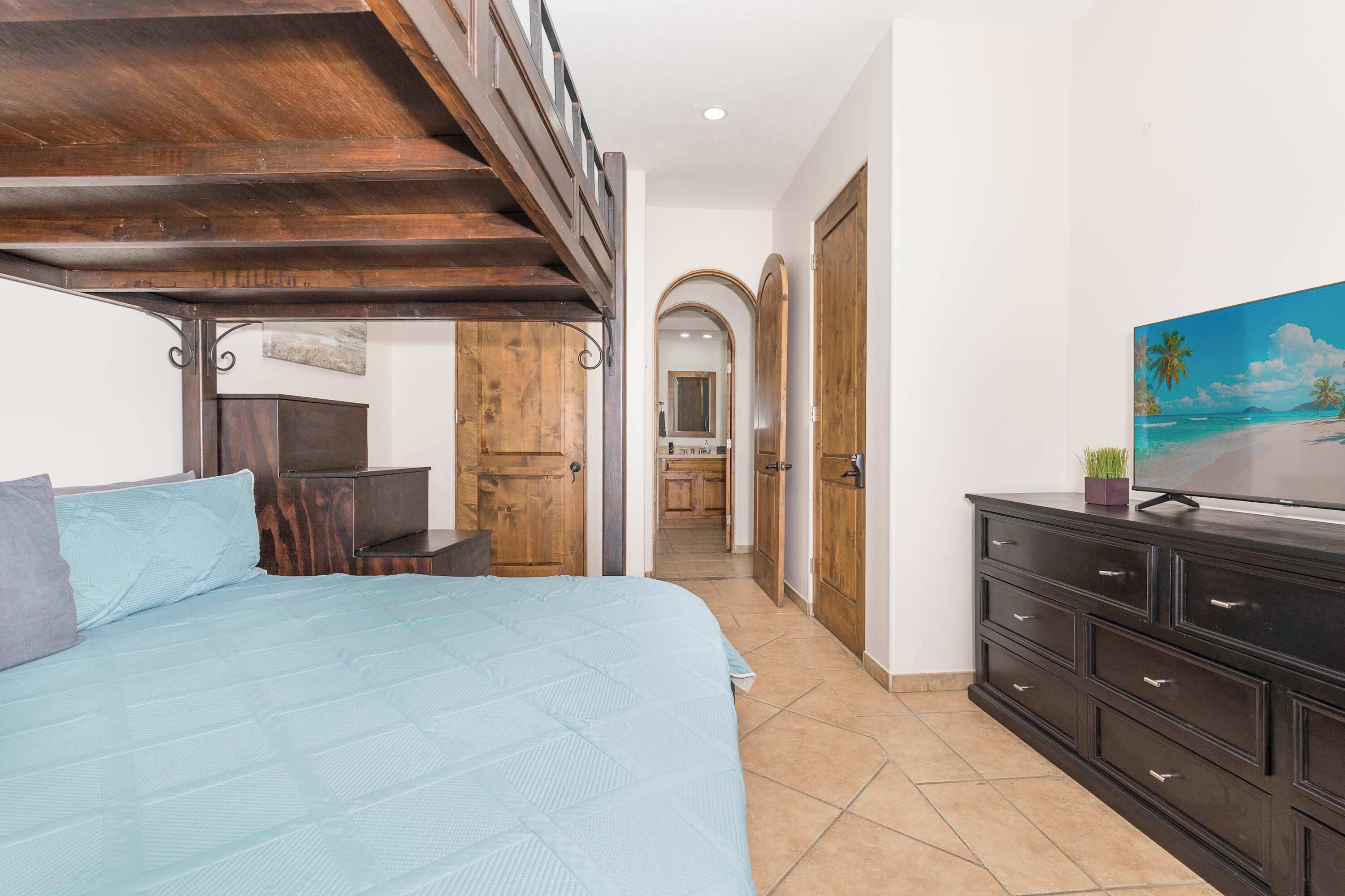 Een slaapkamer met een bed, een houten garderobe en een televisie op een dressoir.