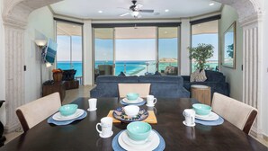 Un comedor con vista al océano, un ventilador de techo y un ventanal grande.