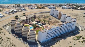 Een kusthotel met meerdere gebouwen, een zwembad en uitzicht op het strand.