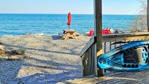 A wooden deck with a view of the sea, a red umbrella, and a kayak. - Lakeside Dreams: Retreat with Stunning Views, private Beach Access (Bowmanville)