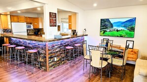 A modern kitchen with wooden cabinets, a stone backsplash, and a bar area with stools. - Lakeside Dreams: Retreat with Stunning Views, private Beach Access (Bowmanville)