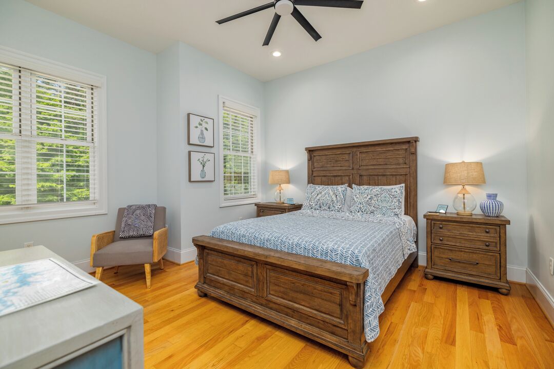 A bedroom with a wooden bed, two bedside tables, a chair, and a desk.