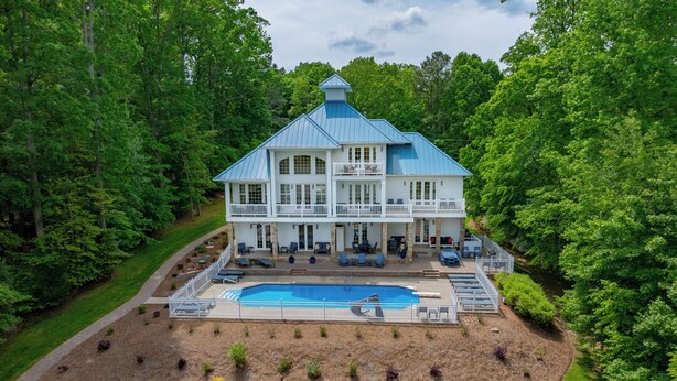 A large, two-story house with a swimming pool in front, surrounded by a well-maintained lawn and trees. - Blue Heaven (Littleton)
