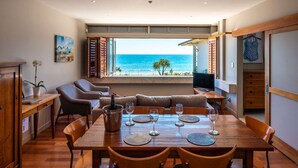 Een eetgedeelte met uitzicht op de oceaan, houten meubels en een televisie op een tafel.