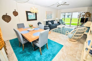 Een moderne woonkamer met een eethoek, een zithoek, een salontafel en uitzicht op het groen.