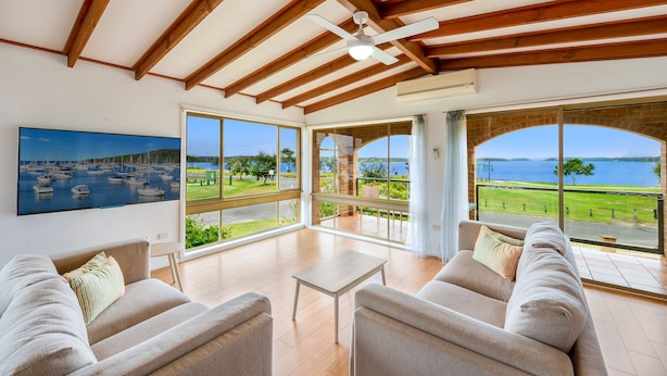A spacious living room with a large window offering a view of a marina and the sea. - 3 Bedroom Waterfront House (Greenwell Point)