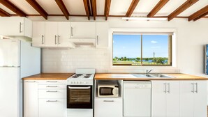 A modern kitchen with white cabinets, a wooden countertop, a built-in oven, a microwave, and a dishwasher. - 3 Bedroom Waterfront House (Greenwell Point)