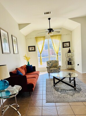A living room with a sofa, a chair, a coffee table, a lamp, and a ceiling fan. - 4BR single story MID & STR Corporate rental Pet friendly home - Kalahari & Dell (Round Rock)