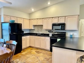 A kitchen with white cabinets, a black refrigerator, a microwave, and a stone floor. - Two bedroom cottage on 8 acres with amazing views. (Paris)