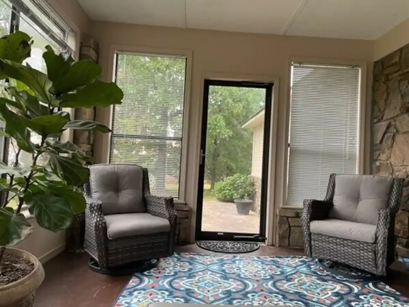 A sunroom with two wicker chairs, a potted plant, and a patterned rug. - Two bedroom cottage on 8 acres with amazing views. (Paris)