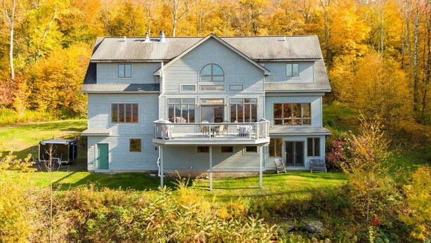 A two-story house with a balcony, surrounded by autumn foliage. - Luxury Mountaintop Estate – Spacious Retreat with Breathtaking Views (Bovina Center)