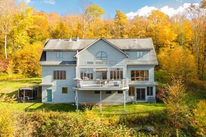 Une maison à deux étages dotée d’un balcon, entourée d’un feuillage automnal.