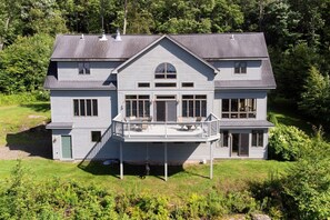Une maison à deux étages avec un balcon, de grandes fenêtres et une porte d’entrée.