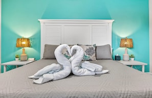 A bed with a white headboard, two nightstands with lamps, and a pair of towels arranged in a heart shape. - Gorgeous 3 bedroom Home With Heated Pool And Pond Access (Largo)