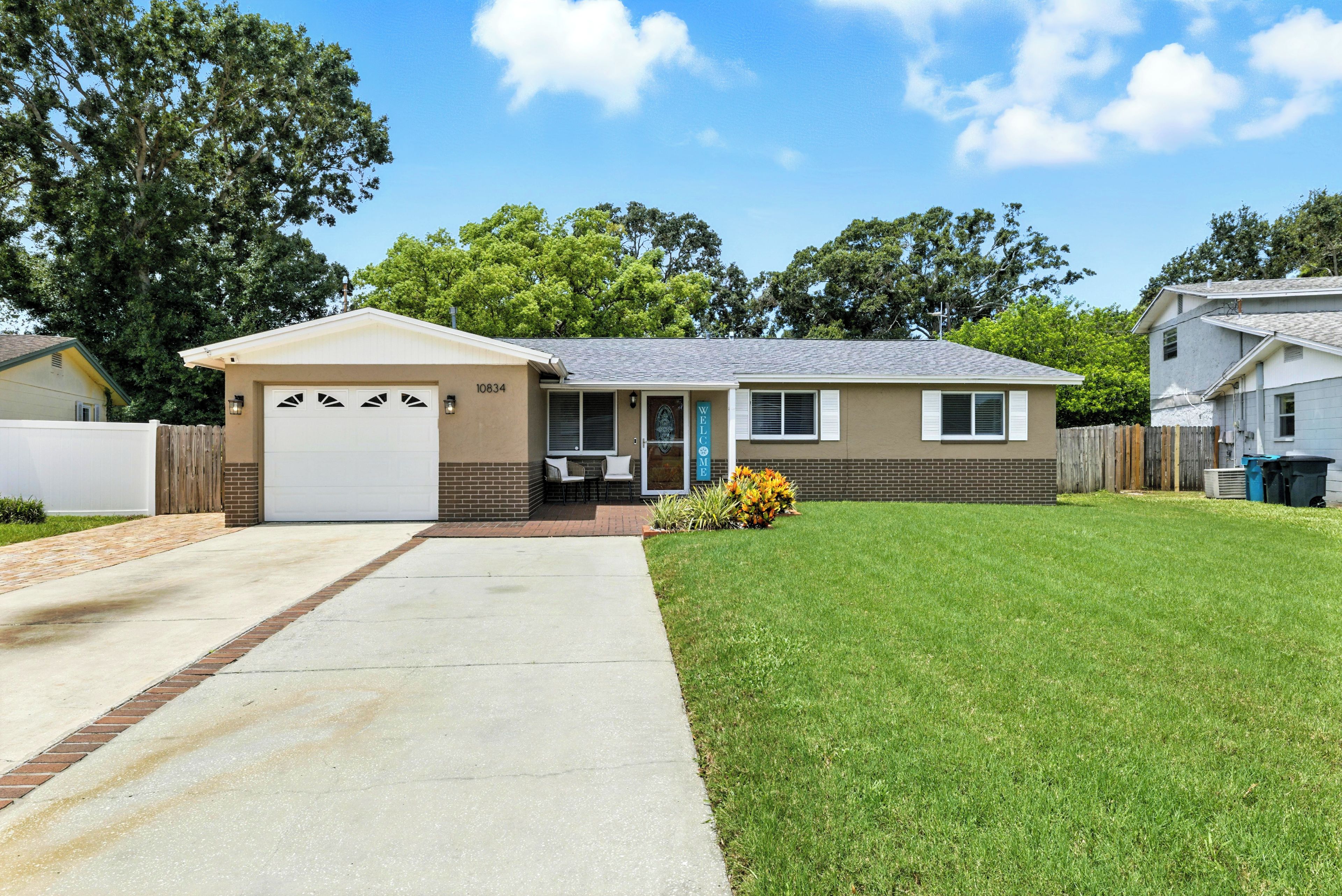 A single-story house with a garage, a front porch with two chairs, and a well-maintained lawn.