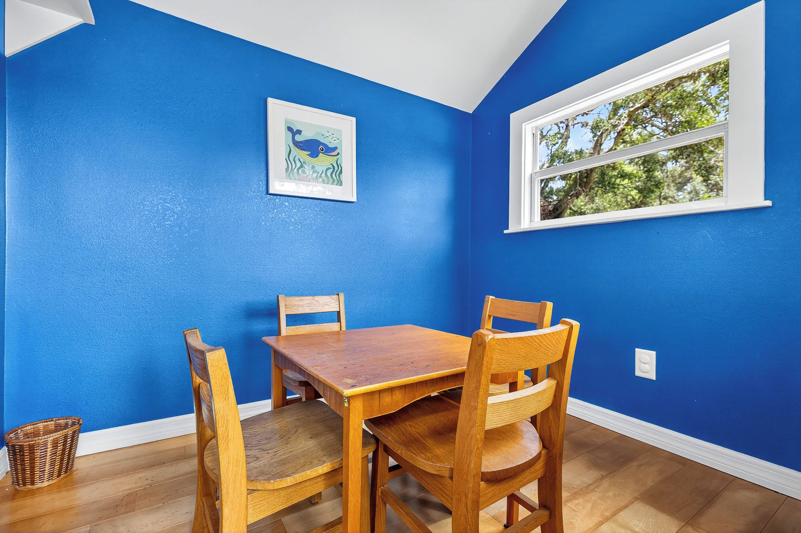 Un coin repas avec un mur bleu, une table en bois et quatre chaises.