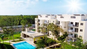 A modern multi-story hotel with a pool area and lush greenery. - Kuxaan Cielo • Style and Comfort Near the Beach. With Rooftop and Swimming Pool. (Playa del Carmen)