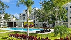A modern pool area with lounge chairs, a clear blue pool, and surrounding greenery. - Kuxaan Cielo • Style and Comfort Near the Beach. With Rooftop and Swimming Pool. (Playa del Carmen)