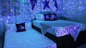 A room with two beds, starfish wall art, and a galaxy-themed light display. - Kuxaan Cielo • Style and Comfort Near the Beach. With Rooftop and Swimming Pool. (Playa del Carmen)
