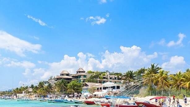 A beach with boats, palm trees, and buildings with thatched roofs. - Kuxaan Cielo • Style and Comfort Near the Beach. With Rooftop and Swimming Pool. (Playa del Carmen)
