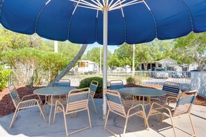 An outdoor patio with a large blue umbrella, metal chairs, and a concrete table. - Resort Pool & Sports Courts! Port Charlotte Home (Port Charlotte)