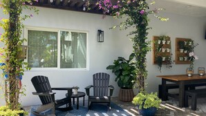 A patio with a pergola, outdoor seating, and potted plants.
