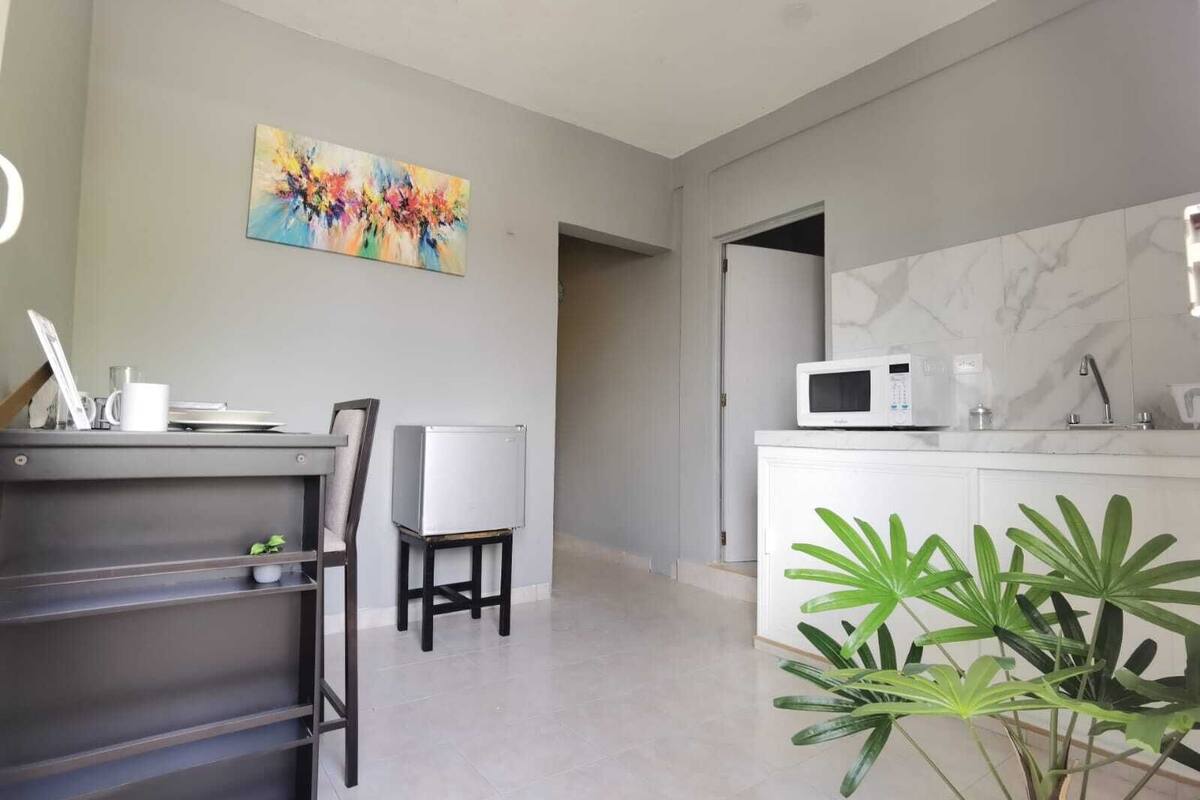 A modern kitchen with a microwave, a coffee maker, and a marble backsplash.
