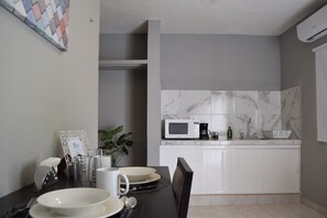 A modern kitchen with white cabinets, a microwave, and a sink.