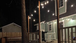 A two-story house with a porch and string lights.