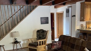 A cozy living room with a wooden staircase, a wooden coffee table, a sofa, and a chair.