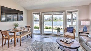 A spacious living room with a large sliding glass door leading to a balcony with a view of a body of water. - Lakefront Bellevue Home: Private Beach & Fire Pit! (Bellevue)