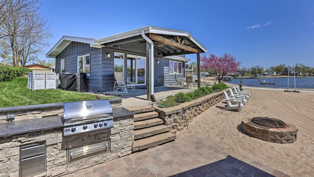 A house with a patio, grill, and a view of the lake. - Lakefront Bellevue Home: Private Beach & Fire Pit! (Bellevue)