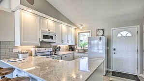 A modern kitchen with white cabinets, granite countertops, and a large island with bar stools. - Lakefront Bellevue Home: Private Beach & Fire Pit! (Bellevue)