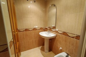Un baño con lavamanos pedestal, espejo y retrete.